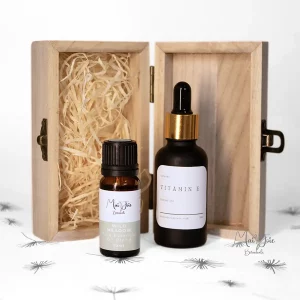 Handcrafted aromatherapy blending kit with a reusable wooden storage box, a sleek black glass dropper bottle of Vitamin E, and a Wild Meadow pure essential oil blend
